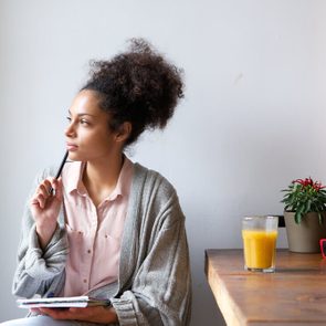 Portrait of a young woman sitting at home with pen and paper