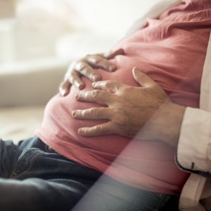 close up of man's hands on stomach