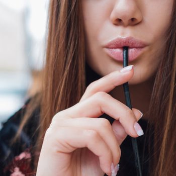 Woman with sexy lips drinking through a straw