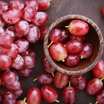 Red grapes on wooden table - vintage filter.