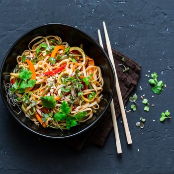 Pad Thai vegetarian vegetables udon noodles in a dark background, top view. Vegetarian food in asian style. Copy space