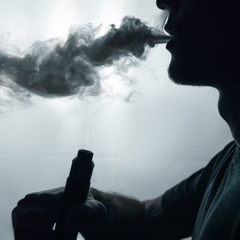 male vapor silhouette exhales a cloud of smoke using an electronic cigarette . copy space