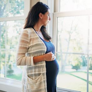 pregnant woman looking out window worried and stressed