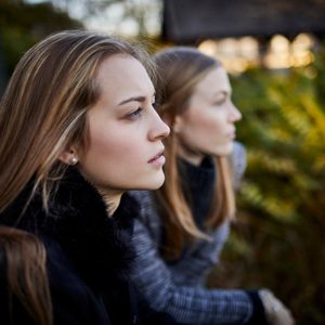 two young women leaning on railing looking at view