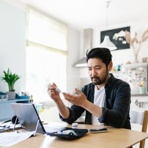 man checking blood sugar while working from home office