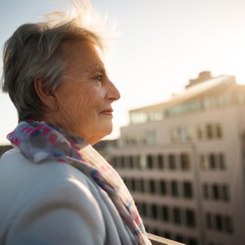 senior woman on balcony during sunset hour