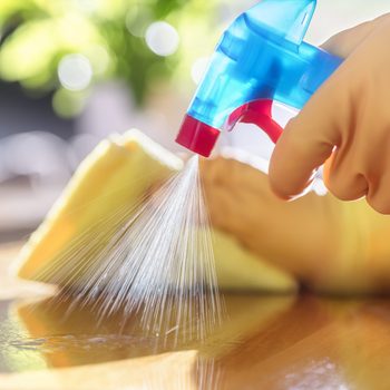 Cleaning with spray detergent, rubber gloves and dish cloth on work surface