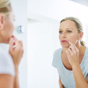 young woman looking at her skin in the mirror