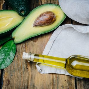 Avocado and avocado oil on a wooden background.