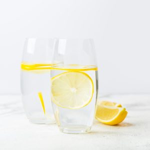 two glasses of lemon water on white background