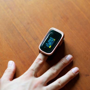 Close-up of a man in hand measuring the oxygen level in his blood with a pulse oximeter