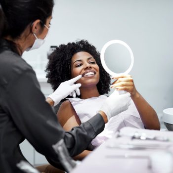 Patient looking teeth in mirror at dental clinic