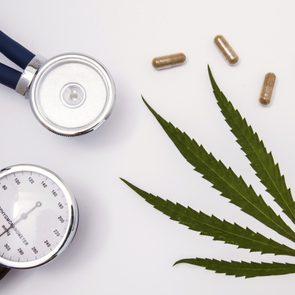 marijuana leaf and blood pressure monitor on white background