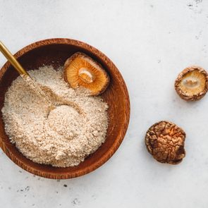 Powder is made from Chinese dried mushrooms Shiitake in a wooden bowl on a table. The concept of medicinal additive for healthy food.