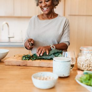 Senior female chopping vegetable at kitchen island