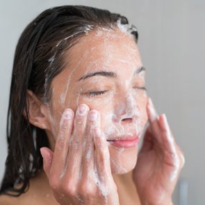 Skincare woman washing face in shower