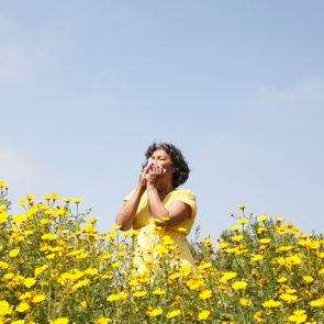 Mixed race woman in field of flowers enjoying scent