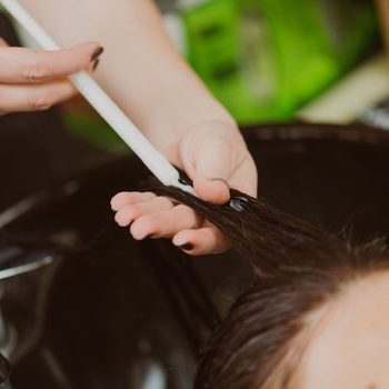 close up of hair stylist applying hair botox to client's hair