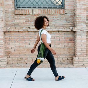 smiling Woman Walking down the sidewalk along a brick building