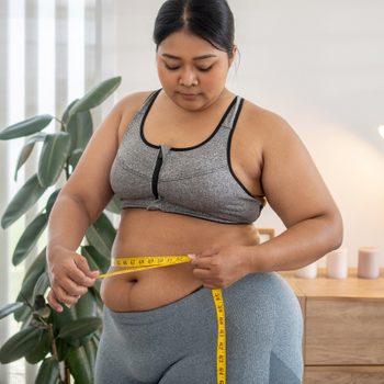 plus size female holds measures tape check her waist size