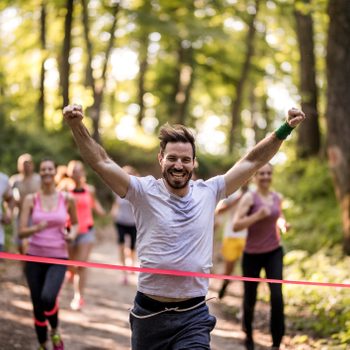 Happy Marathon Runner Winning And Crossing Finish Line With Arms Raised.